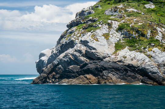 Close-up of Pedra do Macaco rock formation on Pontal do Atalaia peninsula at Guriri cove bay surrounded by blue waters under a bright summer clear blue sky in Arraial do Cabo, Rio de Janeiro - Brazil