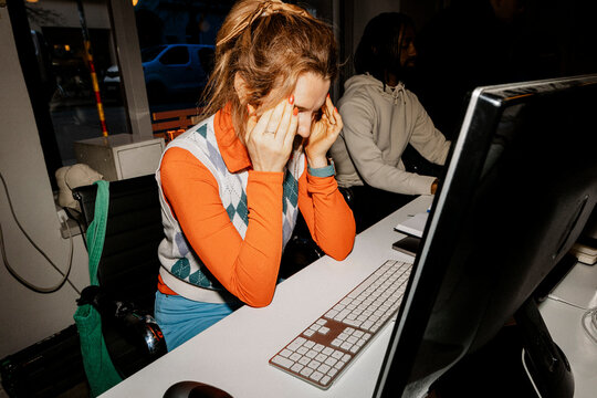 Frustrated female entrepreneur touching temples while sitting at desk in office