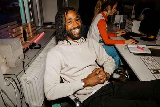 Portrait of happy male entrepreneur relaxing on office chair near desk