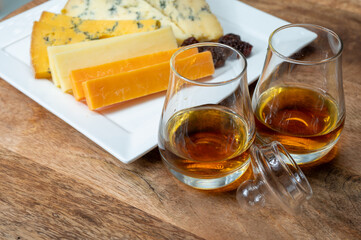 Whiskey and cheese pairing, tasting speyside whisky glasses and plate with sliced cheddar, blue stilton and blue shropshire cheeses, Great Britain food and drink