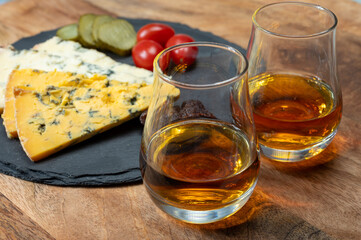Whiskey and cheese pairing, tasting whisky glasses and plate with sliced crumbly old blue stilton and blue shropshire cheeses, Great Britain food and drink