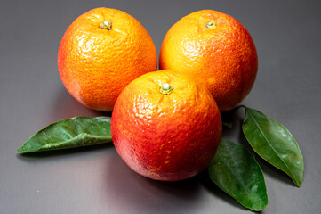 Sicilian sweet juicy yellow and red blood oranges with green leaves close-up