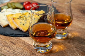 Whiskey and cheese pairing, tasting whisky glasses and plate with sliced crumbly old blue stilton and blue shropshire cheeses, Great Britain food and drink