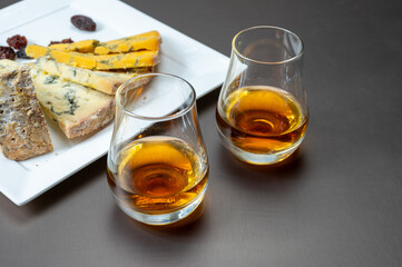 Whiskey and cheese pairing, tasting speyside whisky glasses and plate with sliced cheddar, blue stilton and blue shropshire cheeses, Great Britain food and drink