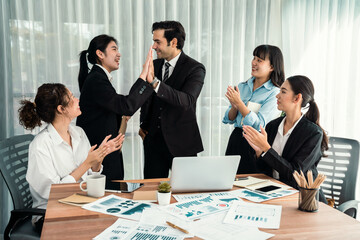 Group of happy businesspeople in high five gesture and successful efficient teamwork. Diverse race office worker celebrate after made progress on marketing planning in corporate office. Habiliment