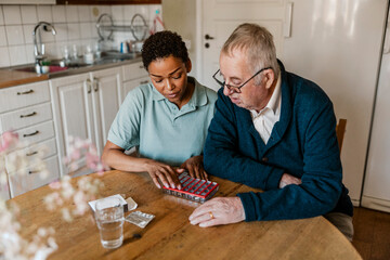 High angle view of female nurse explaining medication dosage to senior man sitting at home