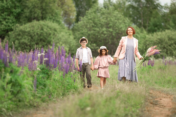 Fototapeta premium Happy caucasian family walking in flower field with children in summer