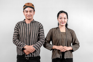 A Indonesian man and a woman, wearing traditional lurik attire expressing a respectful and courteous pose, on a neutral white background.