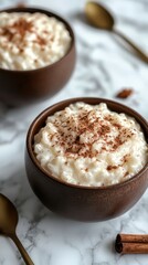 Creamy rice pudding topped with cinnamon in rustic bowls on a marble surface