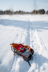 A brightly colored backpack rests atop the undisturbed white snow next to a welltrodden hiking...
