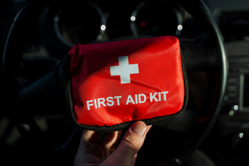 An individual is firmly grasping a first aid kit in their hand, ready to provide assistance in case...
