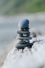 A precise stack of smooth, gray stones balanced on driftwood. Nature's artistry. Ruby Beach, Forks, Washington, USA