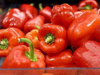 Vibrant red bell peppers are abundant in a market basket, showcasing their freshness and vivid color. Close-up