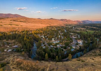 Aerial view of th small town of Winthrop nestled in a valley, beside a river and mountains....
