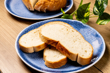 Three slices of French or Italian bread on a blue plate on a wooden table

