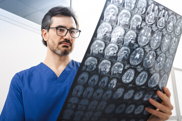 Diagnostics of brain diseases, headaches, tumors and brain cancer with MRI or CT scan. Experienced doctor neurologist looking at MRI scan of patient's head