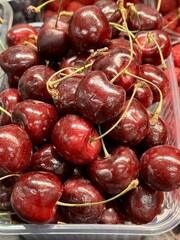 Fresh red ripe cherry in a transparent container for sale on the supermarket counter. A delicious ripe berry for a healthy diet. Close-up