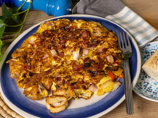 A bacon and cheese omelet with toasted French bread on a blue plate
