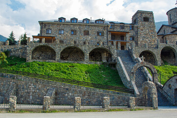 Fototapeta premium Majestic stone monastery sitting on a hillside with lush greenery and stone archways