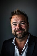 Fototapeta premium Smiling caucasian male adult in suit against dark background