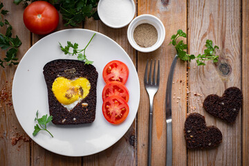 Scrambled eggs in bread for breakfast. Heart-shaped fried eggs on a white plate on a wooden table. close-up