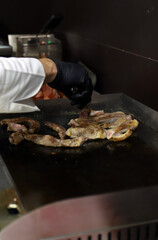 chef cocinero friendo a la plancha panceta de cerdo con herramienta profesional y sus manos con...
