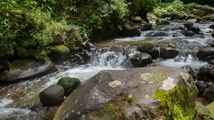 Large stones on the edge of a clear flowing river.Large stones on the edge of a clear flowing...
