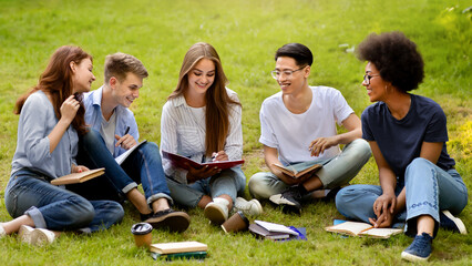 Learning Concept. Group of college friends preparing for lessons outdoors, sitting on lawn in park,...