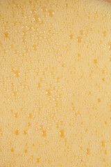A close-up, top-down view of foamy fresh orange juice, highlighting the texture of the bubbles