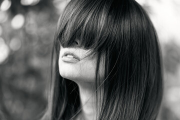 Mysterious woman with hair covering face in dramatic black and white portrait
