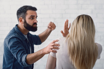 Aggravation of domestic tyranny concept. Scaring woman protecting herself, man in rage beating up his wife