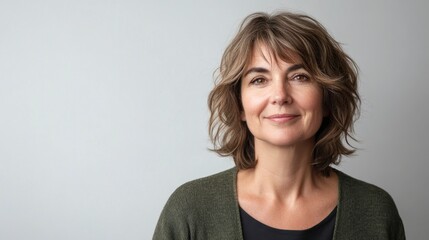 Attractive middle-aged woman with stylish wavy hair and a warm, inviting smile poses in front of neutral background.
