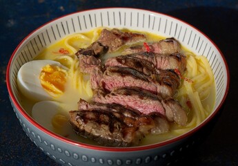 Ramen topped with tender sirloin steak, udon noodles, and a boiled egg.