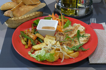 A delectable plate of grilled chicken accompanied by roasted potatoes sauteed vegetables and a...
