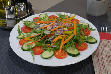 Vibrant salad featuring fresh tomatoes cucumbers carrots onions and peppers artfully arranged on a white plate Healthy dining