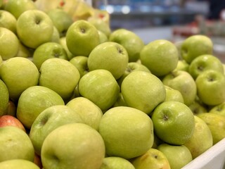 Box filled with fresh natural bio organic green yellow coloured apples placed on counter in local food market. Close-up