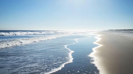 Fototapeta premium Serene Coastal Landscape: Waves Gently Kissing the Sandy Shore Under a Bright Sunny Sky
