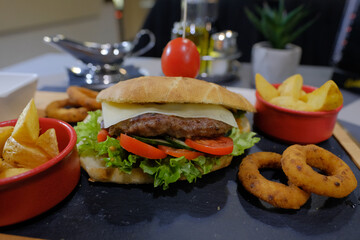 Delicious burger piled high with fresh toppings served with golden fries and crispy onion rings perfect for a satisfying meal