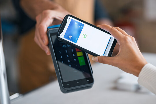 Customer paying for the purchase with her smartphone via NFC in a coffee shop