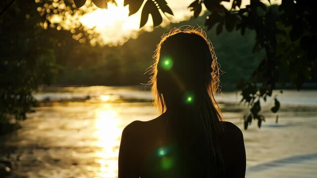 Silhouette of woman by tropical river at sunset revealing tranquil nature beauty, Silhouette of woman in shadows near tropical river steady cam away