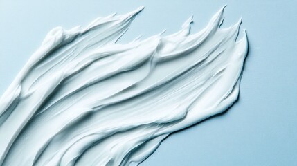 Obraz premium Creamy white moisturizer spread on cool blue surface. Smooth, delicate, skincare product application