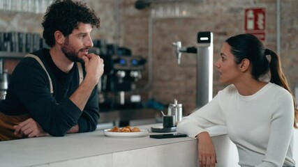 Video of handsome waiter talking with a client while serving chocolate croissants in the pastry shop.