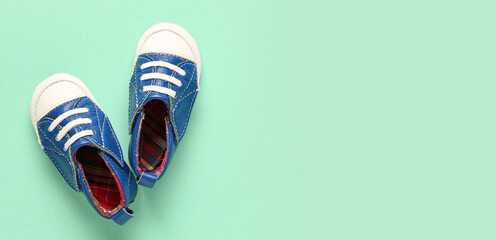 Stylish baby shoes on turquoise background