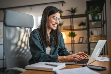 Adult woman work on laptop and use notebook from home office