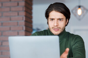 Annoyed guy freelancer looking at laptop screen, working at cafeteria, copy space