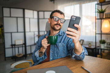 relaxed man drink coffee and use mobile phone from home office