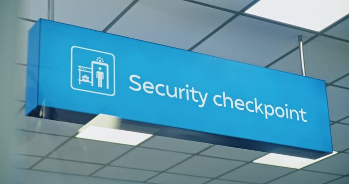 Modern International Airport Terminal: Big LED Blue Security Checkpoint Sign Hanging on Ceiling, Indicates the Location for TSA Passengers Screening, Metal Detector and Luggage Scanning Procedures.