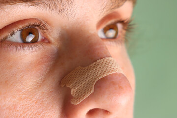 Woman with a nasal strip in the nose apply. Close view of a nasal strip in the nose