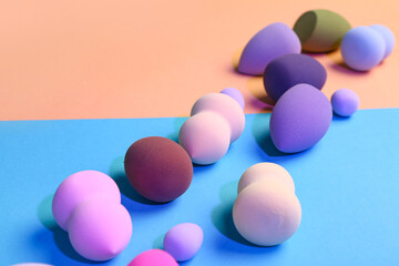 Different makeup sponges on colorful background