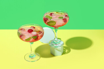 Glasses of fresh raspberry mojito on colorful background
